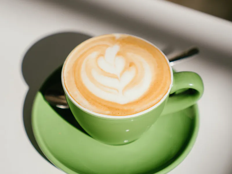 Café de especialidad con leche y arte latte en taza verde