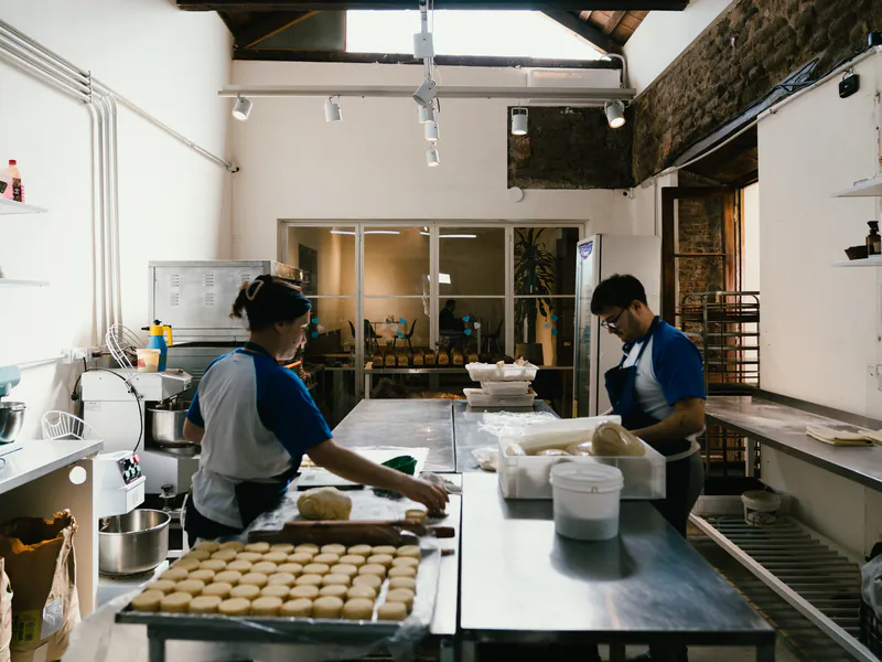 Equipo de honesto bakery produciendo en el obrador, con placas de masa en la mesada