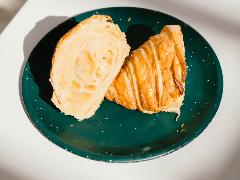 Croissant y medialuna de manteca en plato, laminados de honesto