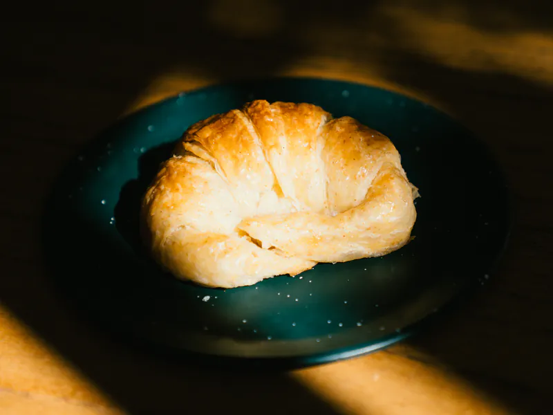 Medialuna hojaldrada en plato, con luz natural de la mañana