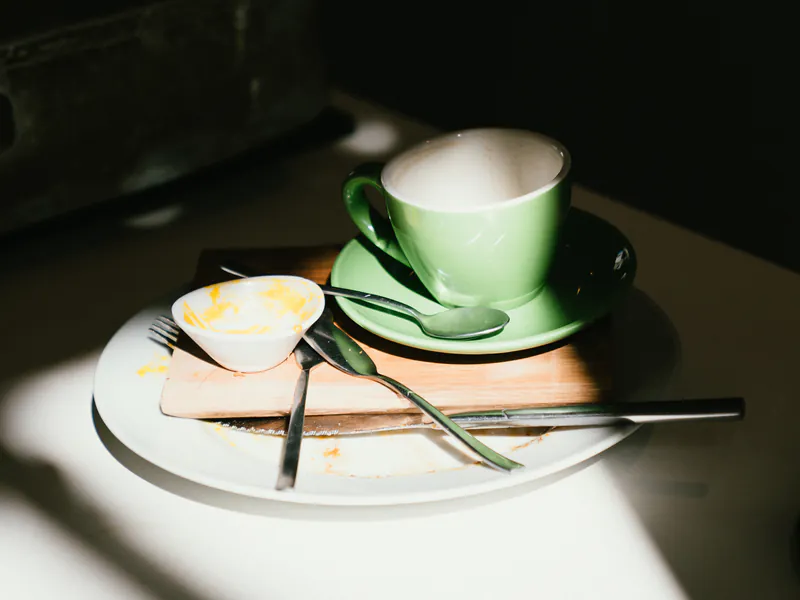Mesa de honesto después del desayuno: taza, plato y manteca con luz natural