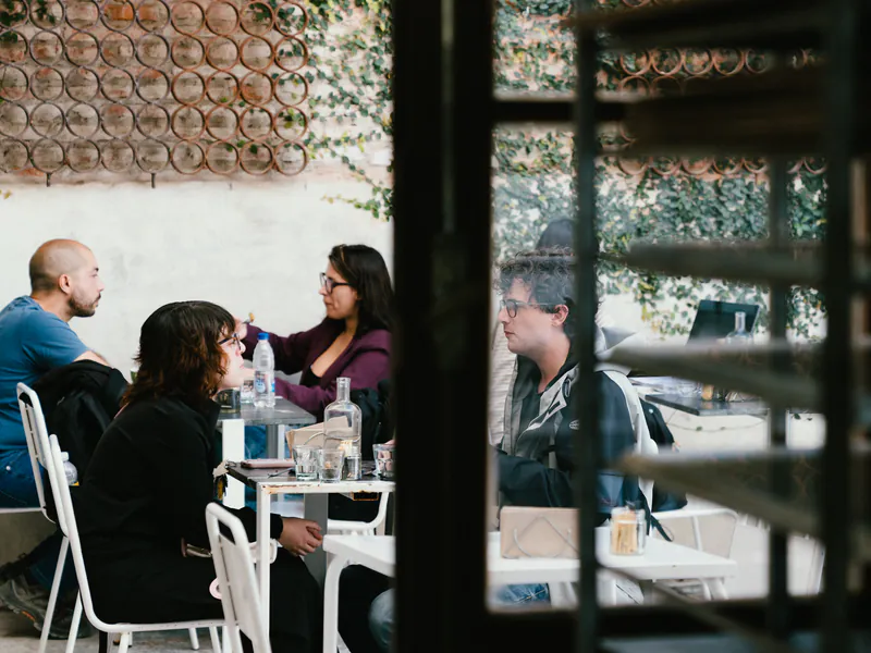 Clientes conversando en las mesas del patio de honesto, con plantas al fondo