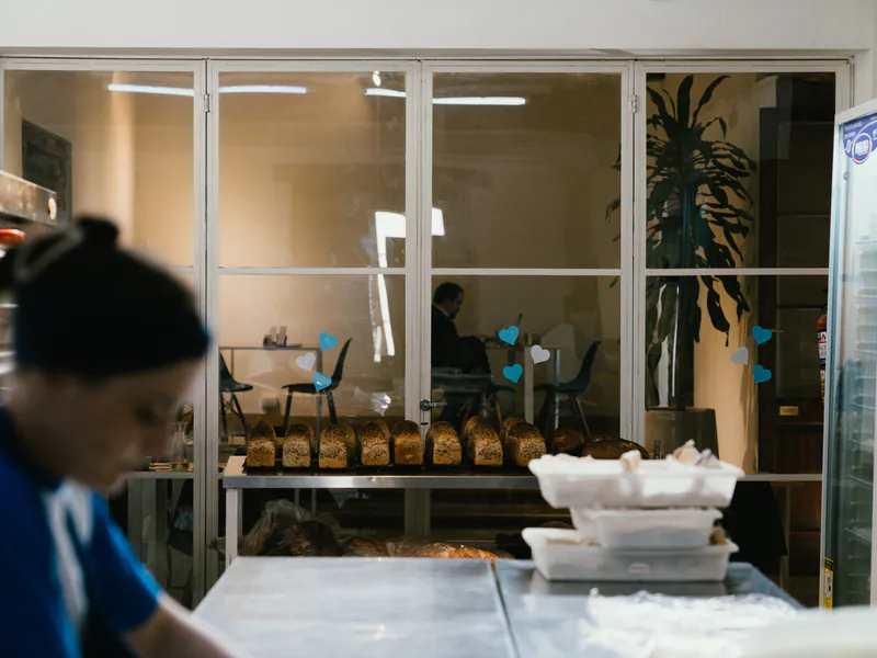 Panadera de honesto trabajando, con la vitrina de panes al fondo
