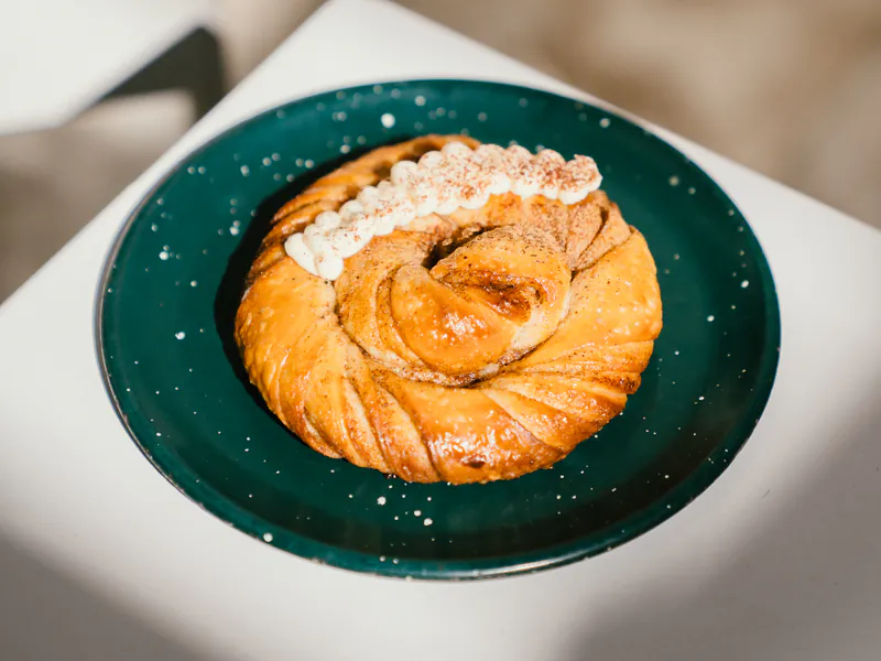 Roll de canela de manteca con azúcar en plato verde, laminado de honesto