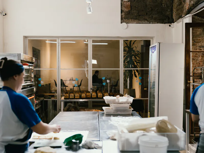 Panadera de honesto trabajando, con la vitrina de hogazas y panes al fondo
